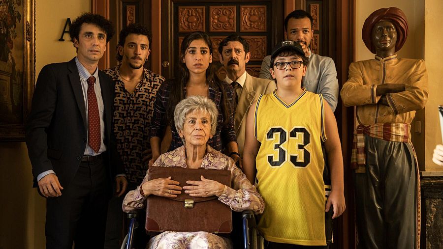 Fotograma de "Sevillanas de Brooklyn" en la que aparece todo el elenco rodeando a la abuela sentada en una silla de ruedas