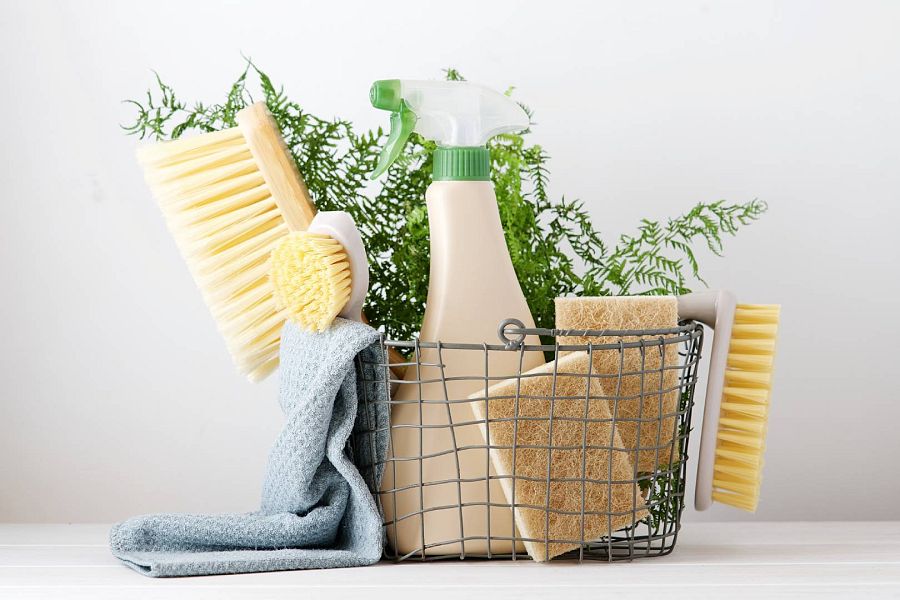 Cesta de metal con estropajos, paños y productos de limpieza