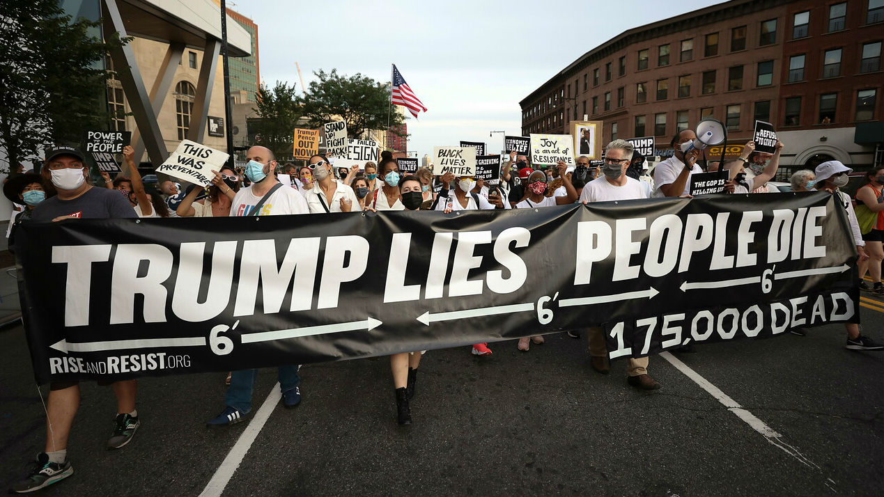 Las personas se reúnen para una vigilia y una 'Marcha por los Muertos' por las víctimas de la pandemia de coronavirus, en Brooklyn, Nueva York, EE. UU. con una pancarta que dice "Trump mienta, la gente muere".
