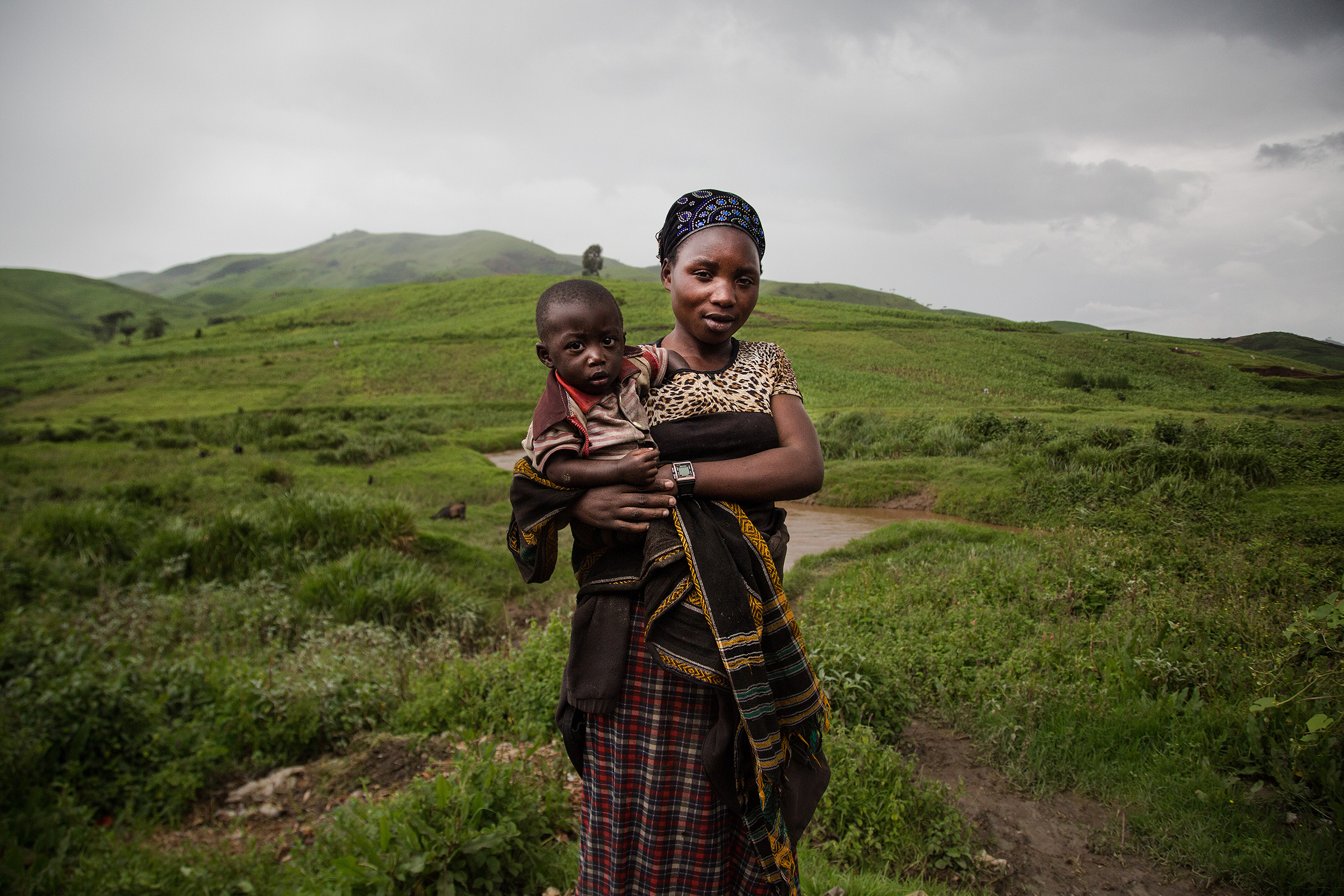 Asefili, una trabajadora del coltn, mira a cmara con su hijo en brazos en medio del campo.