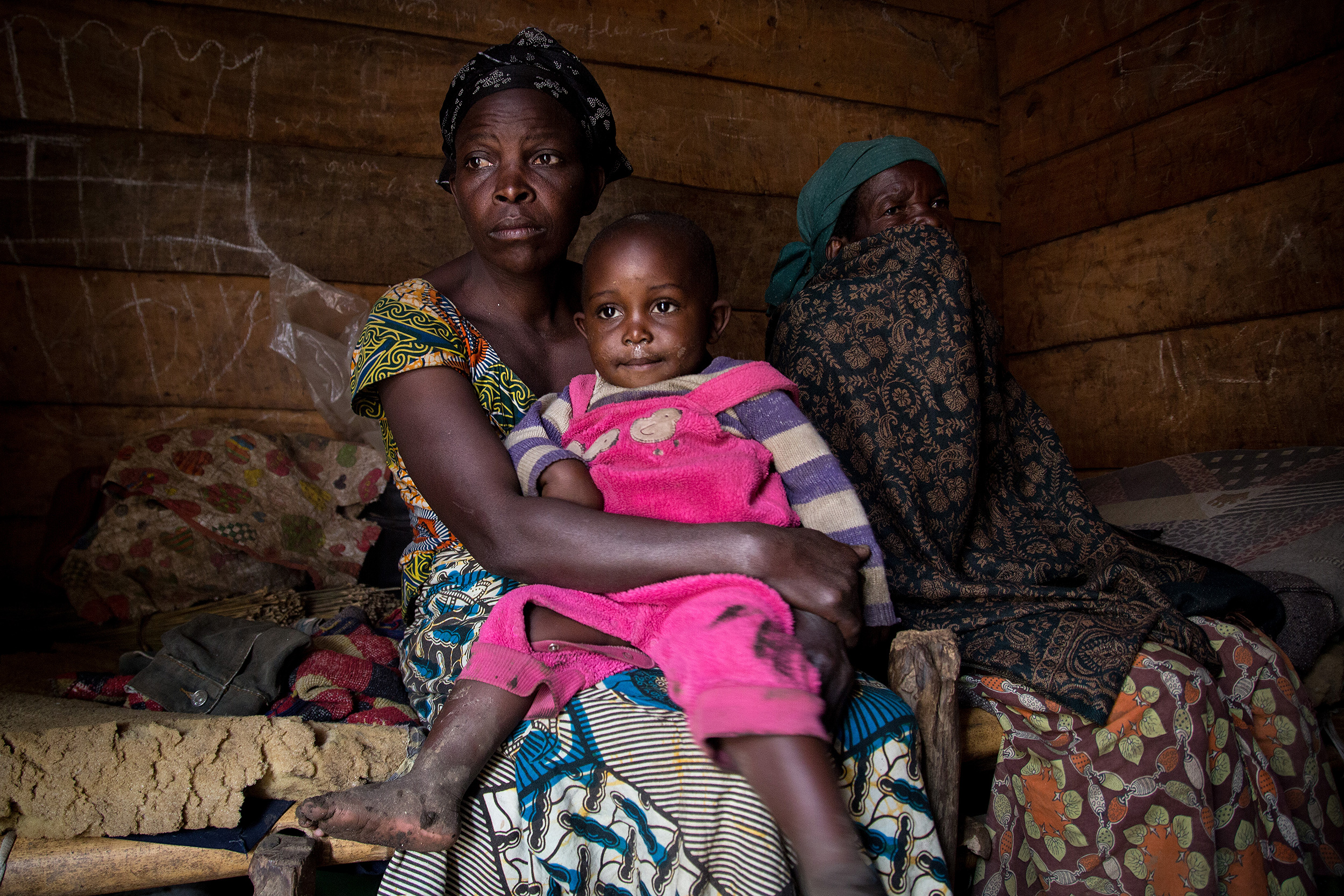 Loabauma con su hija pequea en brazos, junto a una anciana con el rostro tapado, posan sentadas sobre el jergn de su vivienda.