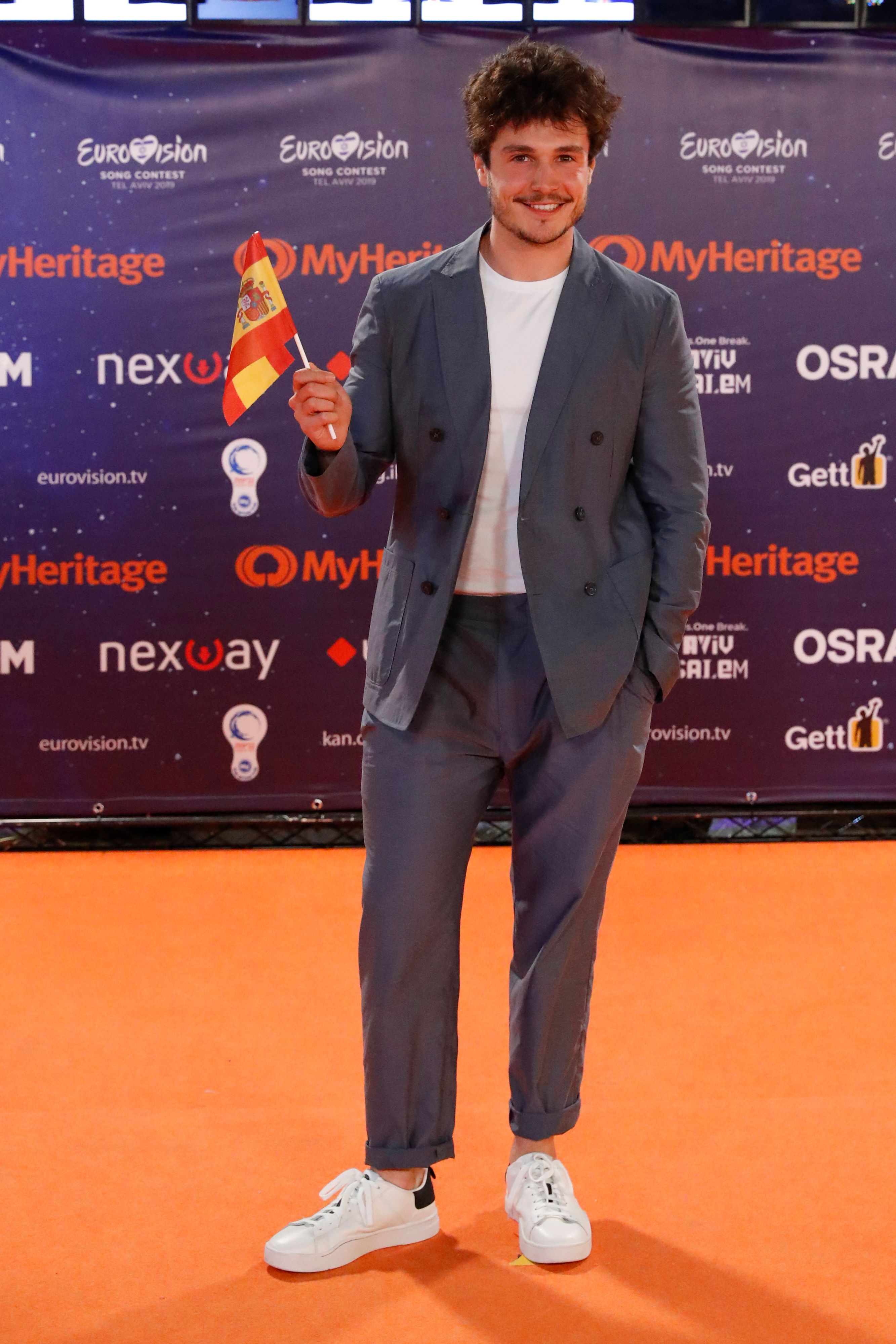 Eurovisión 2019 - Fotos de la Alfombra Naranja de la ceremonia de inauguración Miki ha elegido para la ocasión un total look de Armani con chaqueta cruzada y pantalon ancho en gris azulado, combinado con deportivas y camiseta blancas.