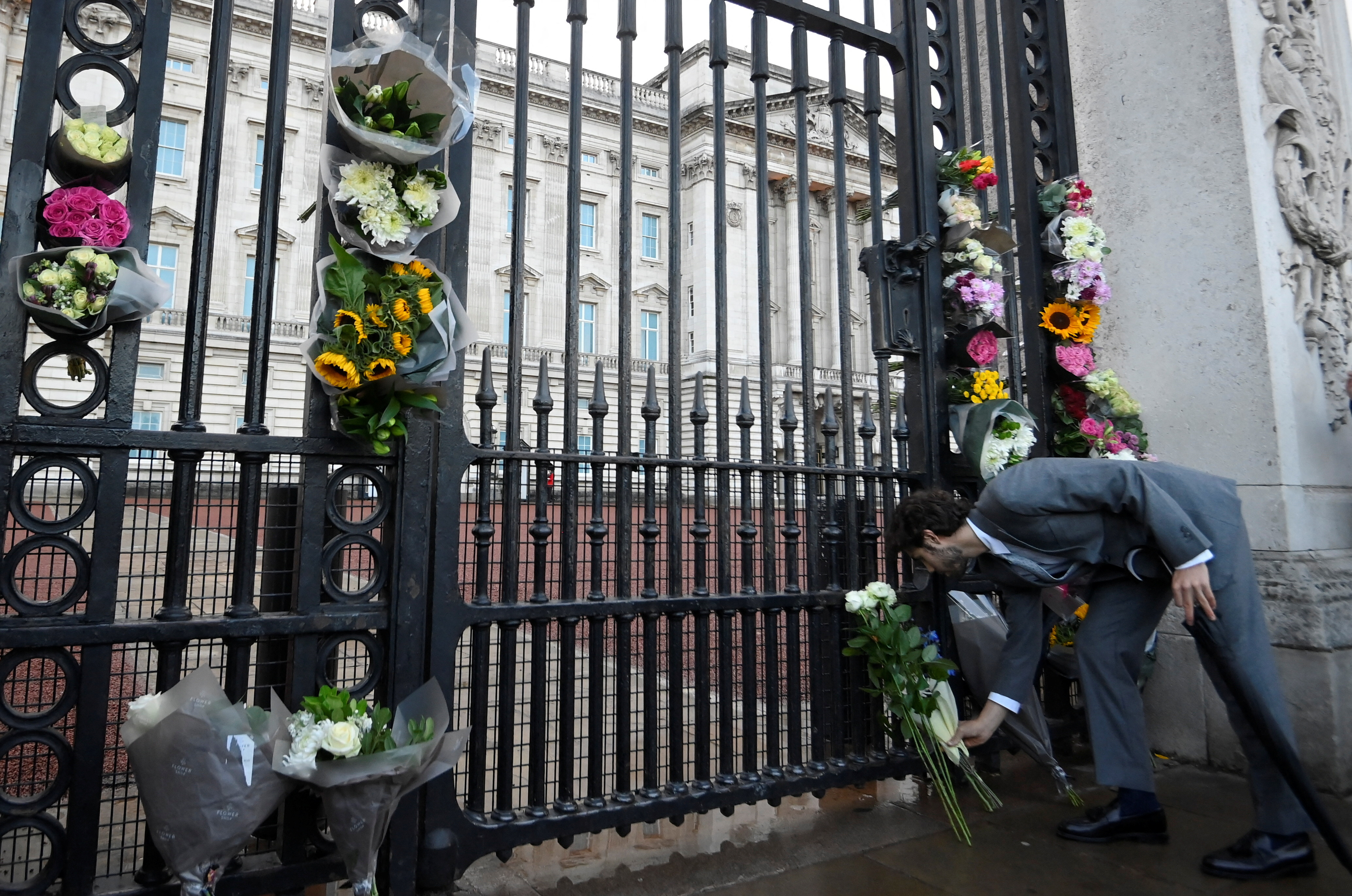 Un hombre deja flores a las puertas del Palacio de Buckingham después de conocerse la noticia de la muerte de Isabel II