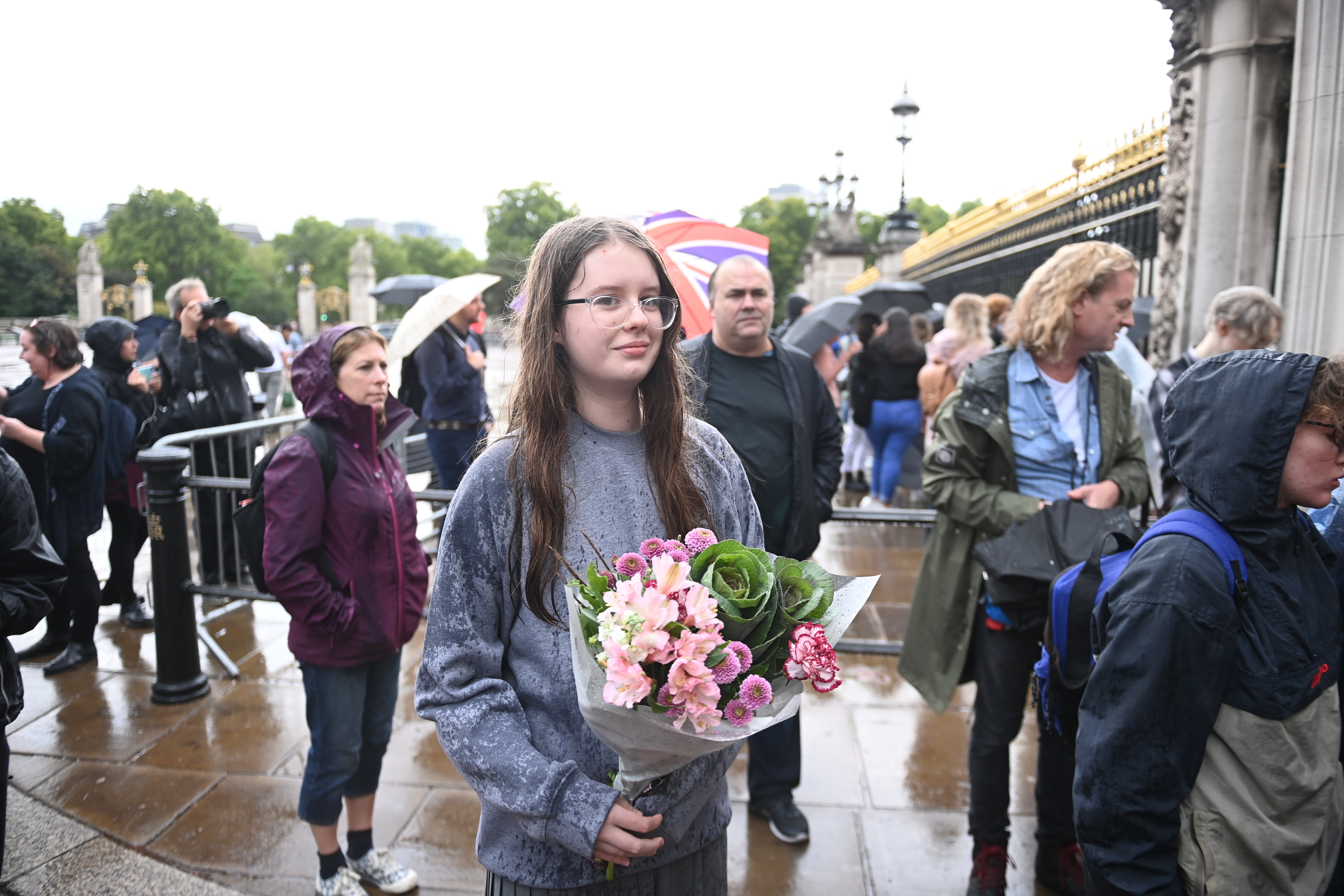 Una joven lleva un ramo de flores al Palacio de Buckingham al informarse del preocupante estado de salud de Isabel II