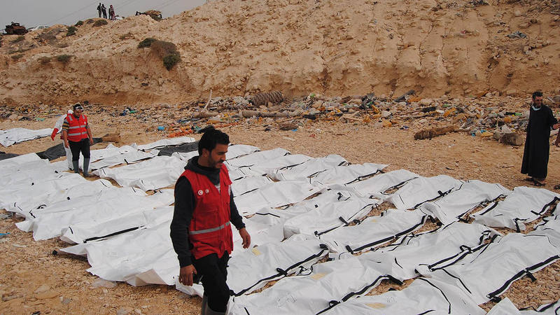 Miembros de la Media Luna Roja de Libia junto a los 74 cuerpos hallados en la playa de Zawiya, en Libia.