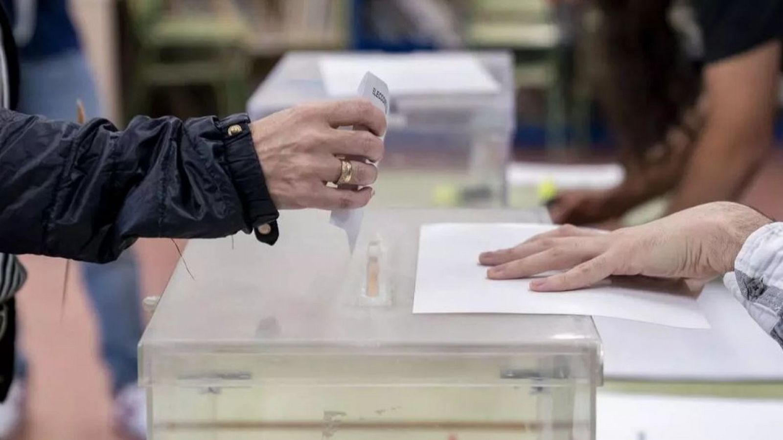Una persona mete su voto en la urna en un colegio electoral