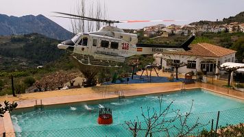 Un helicptero de los Servicios de Emergencia carga agua en una piscina durante los trabajos de extincin del incendio forestal de Trbena