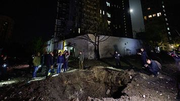 Un grupo de civiles se asoma a un cr�ter que ha dejado un ataque ruso sobre la ciudad de Kharkiv