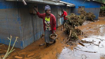 Dos personas limpian los alrededores de su casa en Kenia tras una inundacin