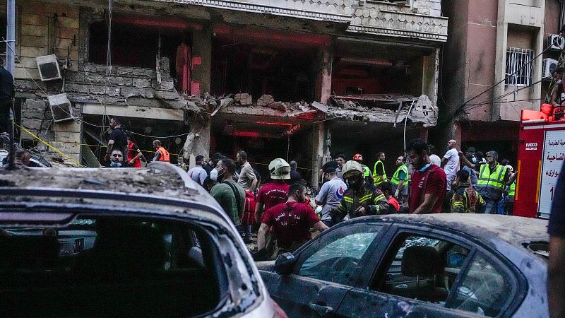 Varias personas y equipos de primeros auxilios frente a un edificio alcanzado por un ataque israel en los suburbios del sur de Beirut