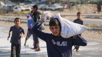 Nios palestinos recogen harina del suelo de una bolsa que cay de un camin de ayuda que circulaba por una carretera en la Franja de Gaza.