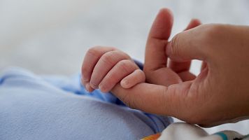 Una persona sosteniendo la mano de un beb