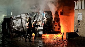 Varias personas apagando un incendio en una furgoneta de la televisin Al Quds en Gaza