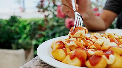 Persona comiendo patatas bravas