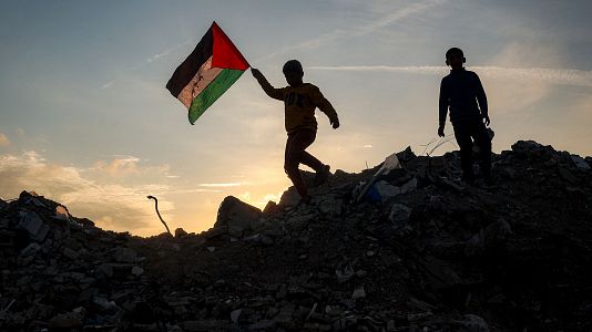 Un nio corre con una bandera palestina sobre una montaa de escombros en un campo de desplazados en el centro de Gaza