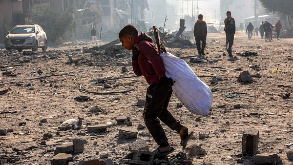 Un nio camina con un saco en medio de los escombros de un bloque residencial en la ciudad de Gaza