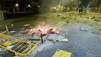 El passeig dels Pasos Catalans de Salt amb pedres a la calada i una foguera fumejant arran dels aldarulls (ACN | Gerard Vil)