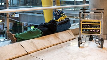 Una persona duerme en la T4 del Aeropuerto Adolfo Suárez-Madrid Barajas