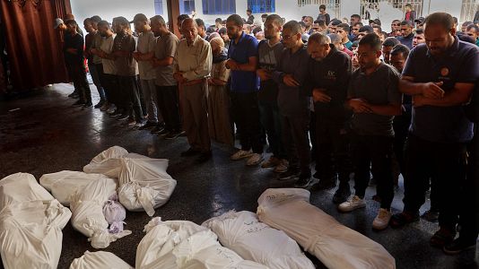 Gazatíes rezan sobre los cuerpos de sus familiares muertos en un ataque aéreo israelí el 20 de mayo en la Franja