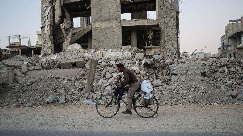 Un hombre sirio pasea en bicicleta entre edificios destruidos en Harasta.