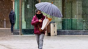 Una dona camina sota la pluja coberta per un paraig�es.