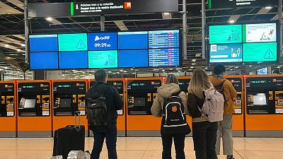 Usuarios de Rodalies de Renfe revisan las pantallas en la estaci�n de Sants, en las que no aparece ning�n tren.