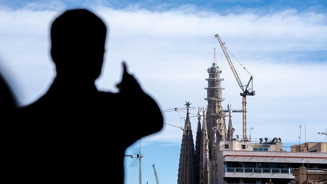 Una persona assenyala la Torre de Jes�s, amb la grua acabant de col�lobar el bra� superior