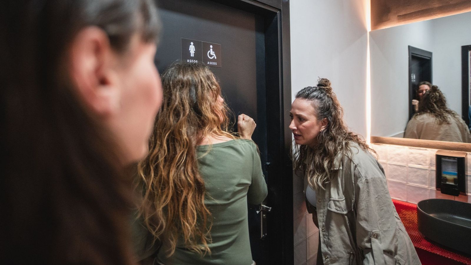 Fila de mujeres esperando frente a la puerta de unos ba�os p�blicos en un entorno urbano, ilustrando la falta de equidad en el dise�o arquitect�nico