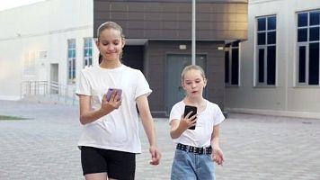 Ni�as usando el m�vil mientras caminan por la calle