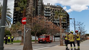 Varios bomberos aguardan junto a los restos del edificio incendiado en el barrio de Campanar de Valencia.