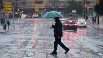 Una persona se protege de la lluvia en M�laga