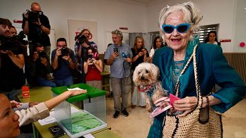 Una mujer acude a votar con su perro debajo del brazo