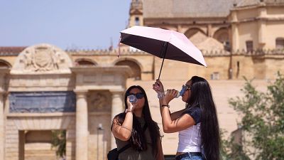 Varias turistas se protegen con paraguas mientras se refrescan ante las altas temperaturas