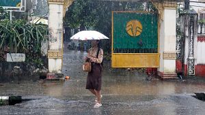 Una mujer camina bajo la lluvia en Yang�n, Myanmar, pa�s que se enfrenta al riesgo de fen�menos meteorol�gicos extremos por El Ni�o combinado con el monz�n del suroeste.
