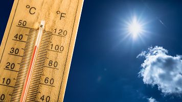 Un term�metro en un d�a de verano muestra la alta temperatura con el sol de fondo