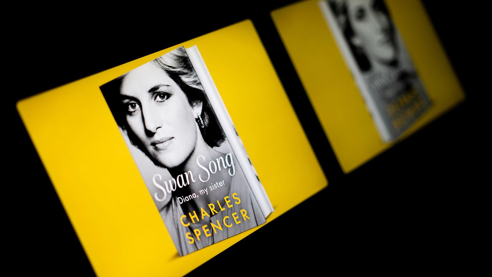 Libro "Swan Song: Diana, My Sister" de Charles Spencer, con retrato de Diana, Princesa de Gales en portada, sobre fondo amarillo y negro.
