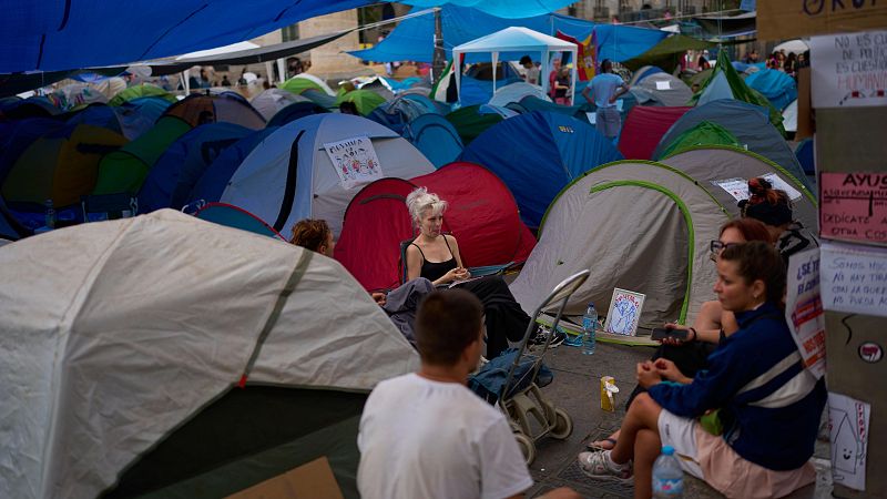Un grupo de personas charla en la acampada por la vivienda en la Puerta del Sol, Madrid