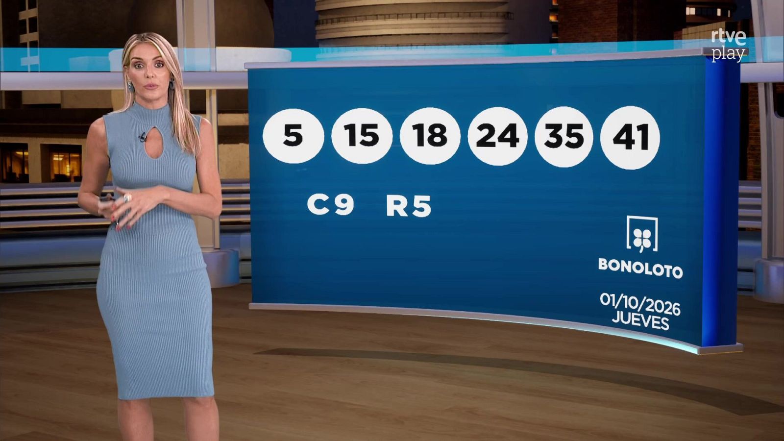 Presentadora en un plató con panel azul que muestra los números ganadores de la Bonoloto y el logotipo del juego.