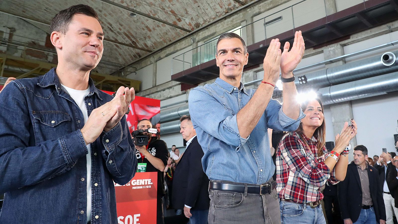 Pedro Sánchez y María Jesús Montero aplauden entusiastas en un mitin político al aire libre frente a una grada de simpatizantes.