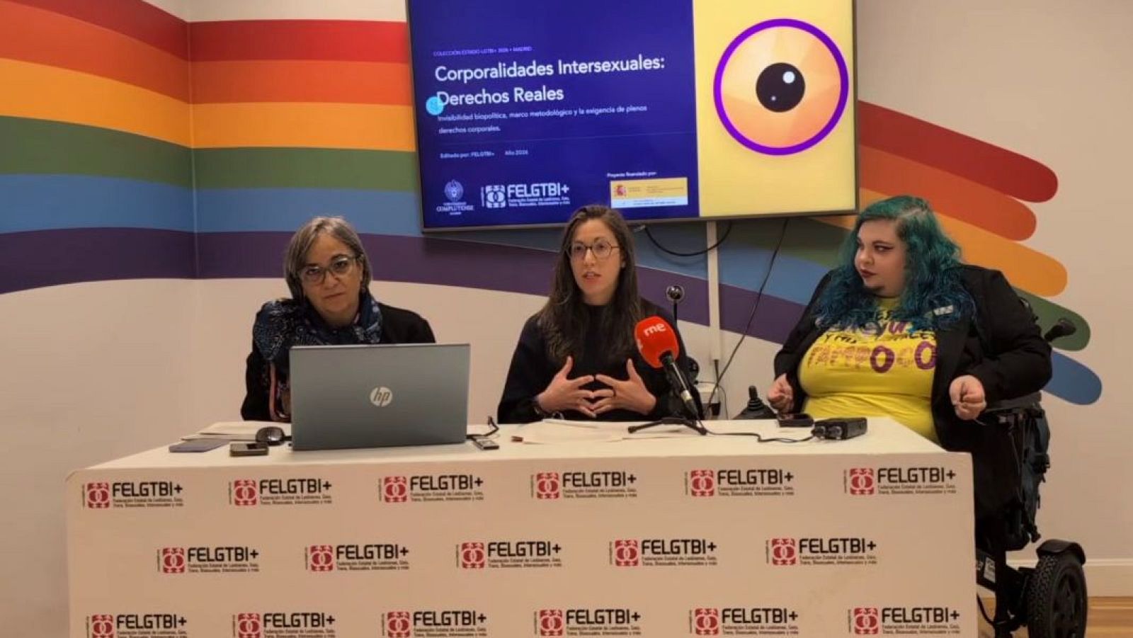 Rueda de prensa sobre corporalidades intersexuales con tres ponentes tras una mesa con el logotipo de la FELGTBI+ y una pantalla con el título de la presentación.