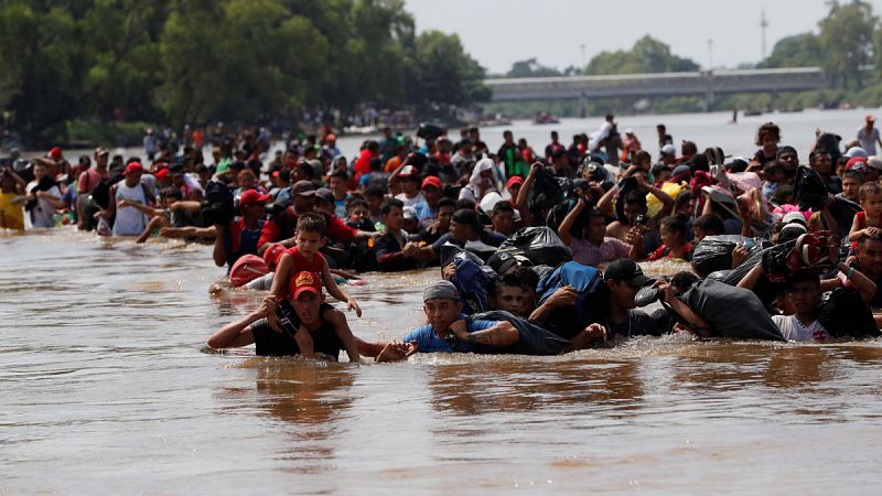La caravana de migrantes cruza a pie el río que separa Guatemala de México