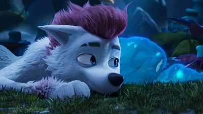 Un lobo blanco con pelo rosa fucsia y ojos azules, recostado sobre hierba, observa algo con curiosidad en un entorno boscoso y oscuro, con elementos mágicos luminosos.