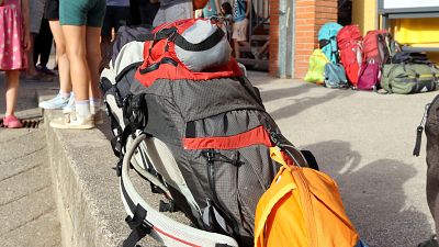Mochilas de senderismo de varios colores y tamaños, junto a las piernas de personas, algunas con ropa de verano, en un día soleado. Mochilas de senderismo de varios colores y tamaños, junto a las piernas de personas, algunas con ropa de verano, en un día soleado.