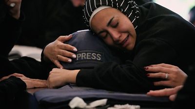 Zainab, hermana de la periodista libanesa Amal Khalil, quien murió el miércoles en un ataque aéreo israelí, abraza su casco mientras llora junto a su ataúd en la aldea de Baysariyeh, al sur del Líbano, el jueves 23 de abril de 2026.