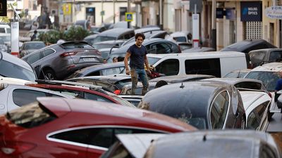Graves inundaciones en Valencia dejan coches apilados y cubiertos de lodo. Un hombre inspecciona los daños caminando sobre los vehículos. Graves inundaciones en Valencia dejan coches apilados y cubiertos de lodo. Un hombre inspecciona los daños caminando sobre los vehículos.