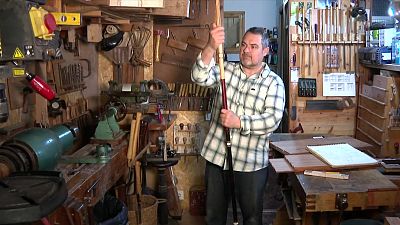 Òscar Ollé, ebanista, posa en el seu taller amb un bàcul de fusta tallat per ell mateix. L'espai està ple d'eines i maquinària d'ebenisteria. Òscar Ollé, ebanista, posa en el seu taller amb un bàcul de fusta tallat per ell mateix. L'espai està ple d'eines i maquinària d'ebenisteria.