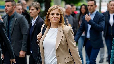Isabel Díaz Ayuso, con americana beige y bolsa negra, camina en un entorno público y formal. Su expresión es seria y relajada. Isabel Díaz Ayuso, con americana beige y bolsa negra, camina en un entorno público y formal. Su expresión es seria y relajada.