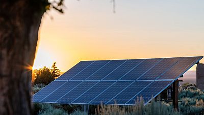 Paneles solares al atardecer, iluminados por el sol poniente. Instalación en entorno natural con vegetación, representando comunidades solares. Paneles solares al atardecer, iluminados por el sol poniente. Instalación en entorno natural con vegetación, representando comunidades solares.