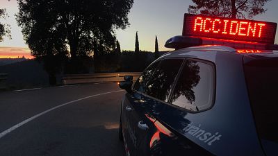 Coche patrulla de los Mossos d'Esquadra señalizando un accidente de tráfico en una carretera con curvas. Panel luminoso con la palabra 'ACCIDENT' visible. Coche patrulla de los Mossos d'Esquadra señalizando un accidente de tráfico en una carretera con curvas. Panel luminoso con la palabra 'ACCIDENT' visible.
