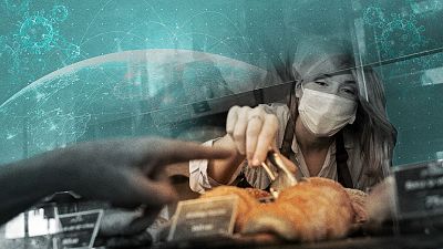 Dependienta con mascarilla sirve comida con pinzas a cliente tras mampara protectora. Imagen superpuesta muestra mapa mundial con virus, simbolizando el impacto global de la pandemia. Dependienta con mascarilla sirve comida con pinzas a cliente tras mampara protectora. Imagen superpuesta muestra mapa mundial con virus, simbolizando el impacto global de la pandemia.